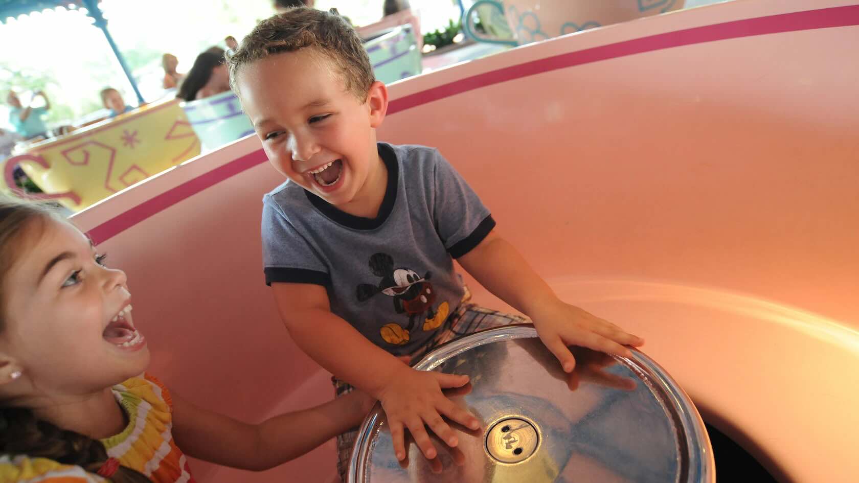 Two kids having fun spinning in the teacups ride